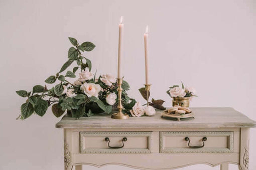 Elegant shabby chic table styling with pale pink taper candles, roses, and vintage floral decor.