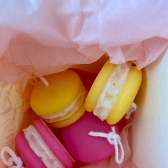Colorful macarons in a decorative paper bag with pink tissue paper.