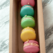 Colorful scented macaron candles in a gift box, featuring pink, green, yellow, and blue colors, handmade eco-friendly soy.