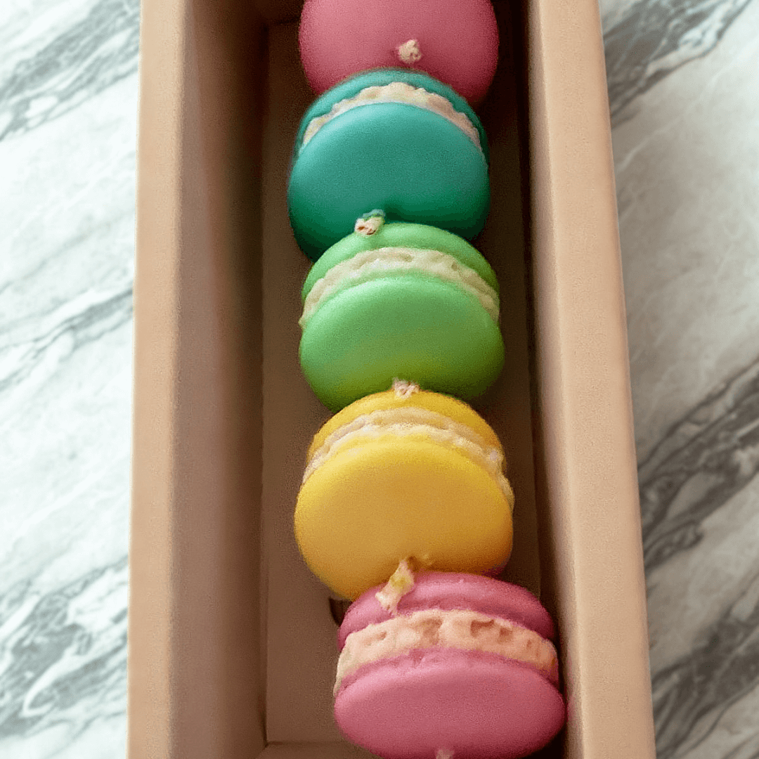 Colorful scented macaron candles in a gift box, featuring pink, green, yellow, and blue colors, handmade eco-friendly soy.