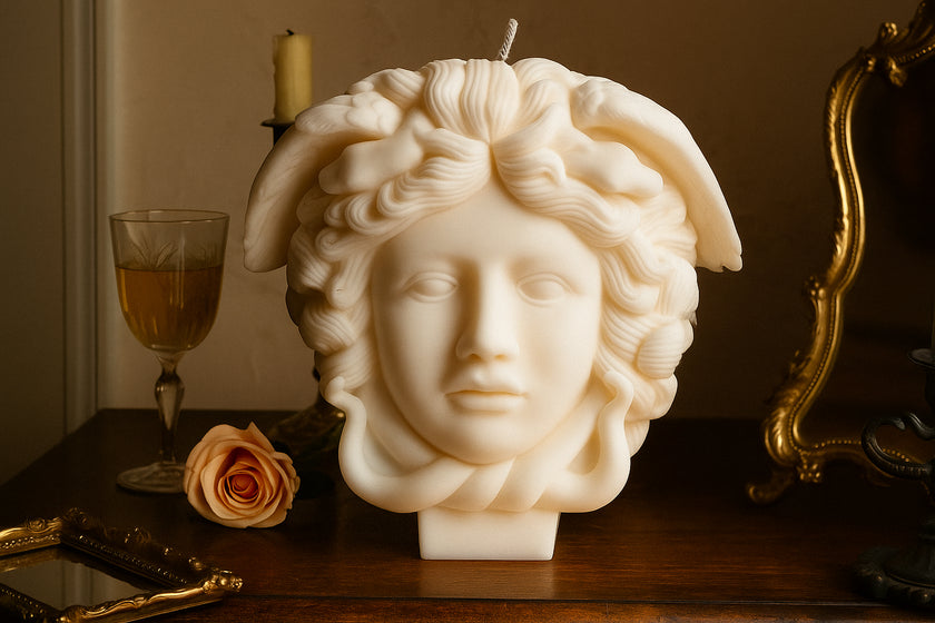 Intricately detailed Medusa head candle with lifelike sculpted snakes, displayed on a vintage wooden table with a rose and antique mirror in the background.