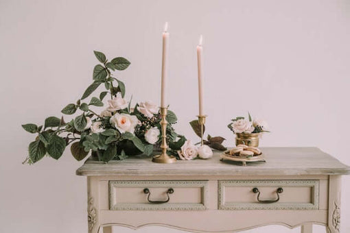 Elegant shabby chic table styling with pale pink taper candles, roses, and vintage floral decor.