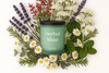 Votive Herbal Muse soy candle in matte green jar surrounded by fresh lavender, chamomile, mint, rosemary, and white wildflowers — eco-friendly aromatherapy candle for relaxation, wellness, and sustainable home fragrance.