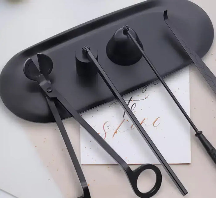 Black wick trimmer, snuffer and dipper candle tool set on a tray