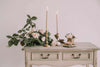 Elegant shabby chic table styling with pale pink taper candles, roses, and vintage floral decor.