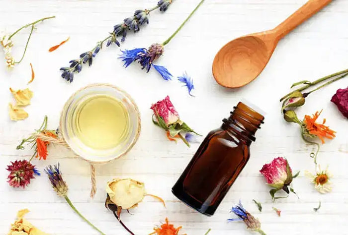 Amber essential oil bottle with dried flowers and a wooden spoon, flat lay