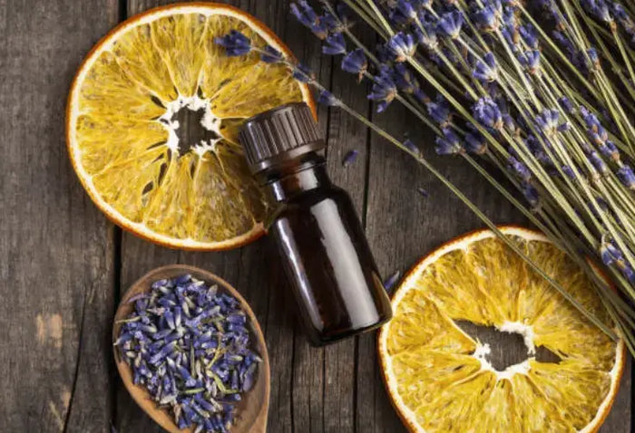 Essential oil bottle with dried orange slices and lavender on dark wood