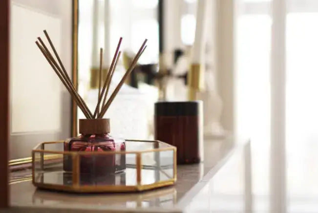 Reed diffuser on a gold and glass tray in a bright room