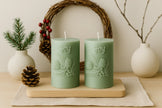 Two green candles with 'Joy' text on a wooden board, surrounded by decorative items.