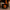 Black tin candle with a skull design on a wooden surface with pumpkins and a candle in the background