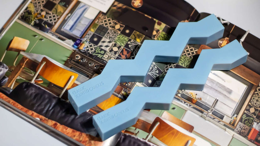 Stylish blue sculptural candle piece featured on a magazine page showcasing modern interior design.