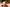 Pink textured candle on a wooden stump with Christmas decorations in the background