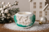 Decorative candle holder with animal designs on a snowy surface with Christmas decorations.
