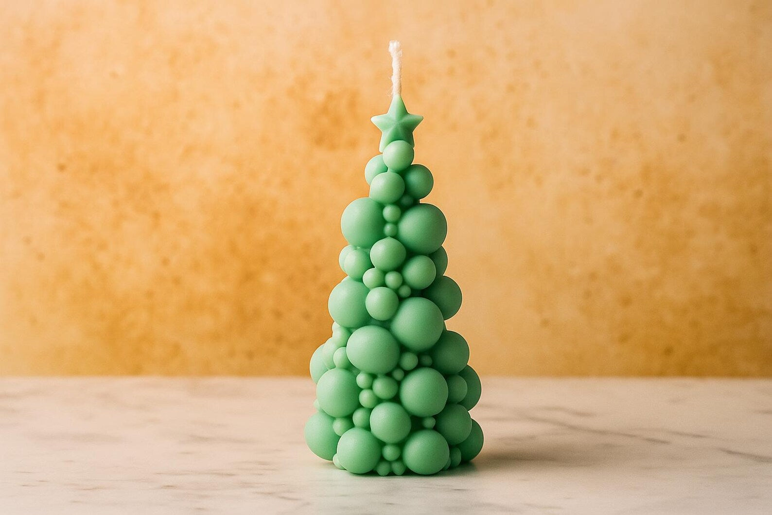 Green bubble-patterned candle shaped like a Christmas tree on a wooden surface with a beige background