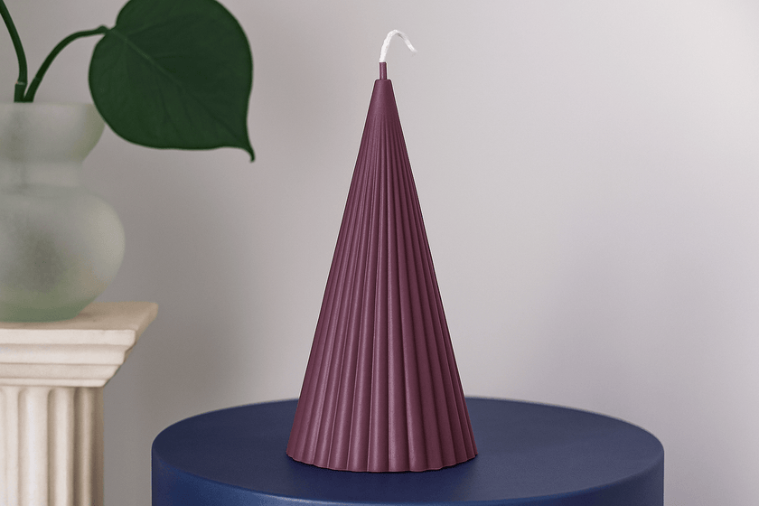 Purple textured candle on a blue surface with a neutral background