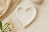Heart-shaped ceramic dish on a beige fabric background with flowers