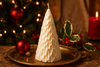 Decorative candle shaped like a Christmas tree on a gold plate with festive background