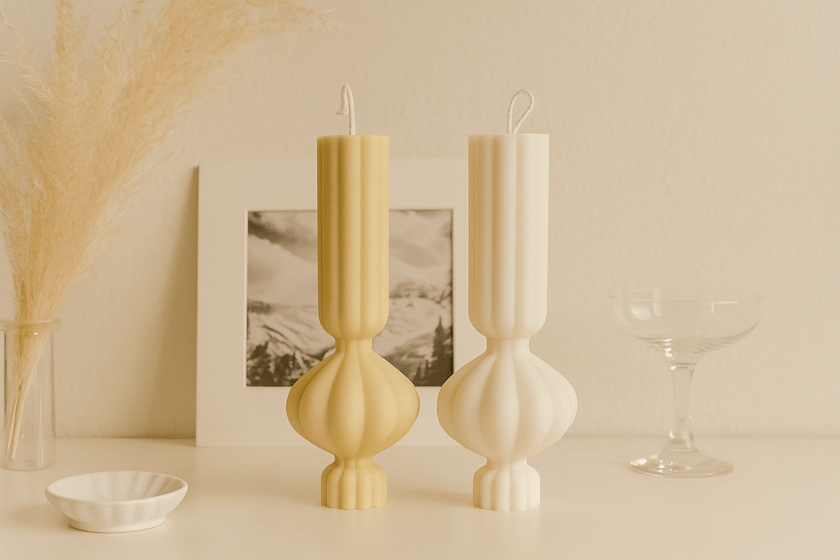 Two decorative candles on a surface with a neutral background