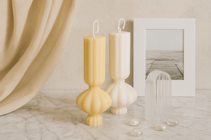 Decorative candles with unique shapes on a marble surface next to a framed picture.