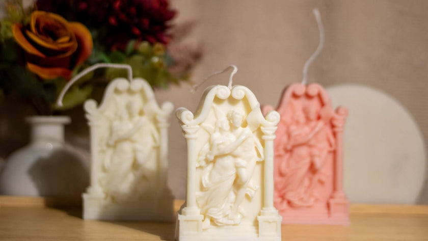 Decorative soy wax sculptures for lovers in white and pink, featuring intricate designs on a wooden surface.