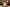 Decorative white candle shaped like a Christmas tree on a table with a glass and other candles in the background.