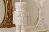 White nutcracker candle on a surface with decorative background