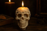 Skull-shaped candle with a lit wick on a dark background