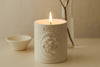White candle with 'Cupid' Votive branding on a beige surface