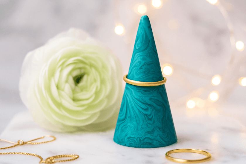 Teal marbled ring holder with gold rings on a light background