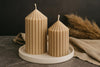 Two ribbed beeswax candles on a white tray with a dark background