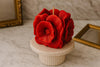 Red flower-shaped candle on a marble surface with gold frames in the background