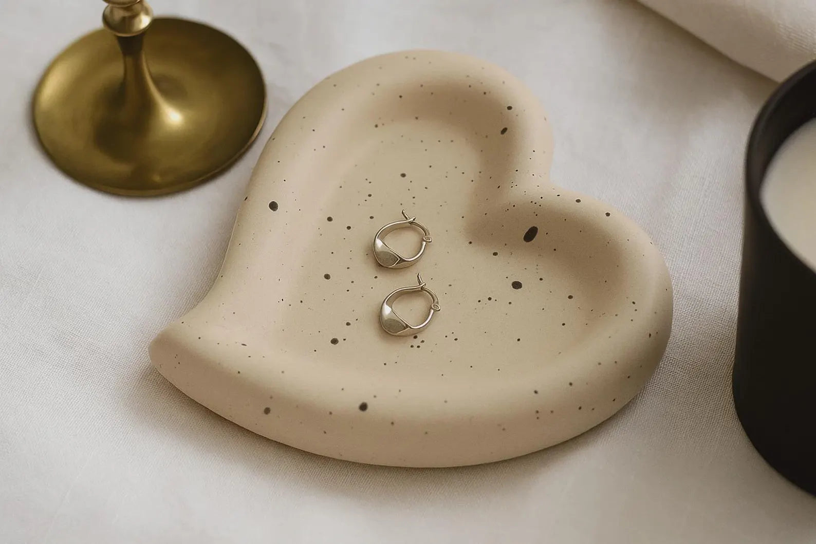 Heart-shaped ceramic dish with earrings on a light surface