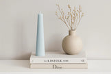 Striped Candle and vase on top of books with a neutral background