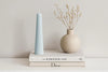 Striped Candle and vase on top of books with a neutral background