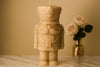Candle shaped like a nutcracker with a vase of flowers in the background