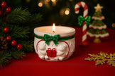Decorative candle with Christmas-themed design on a red surface with festive decorations.
