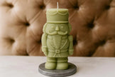 Green nutcracker-shaped candle on a gray base against a brown textured background