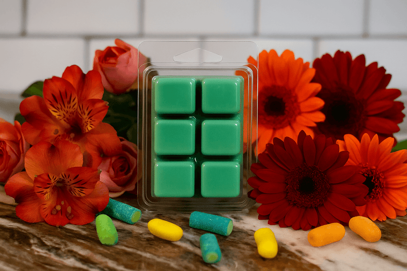 Green wax melts in clear packaging on a marble surface with a blurred background