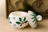 Decorative ceramic pot with holly design on a neutral background