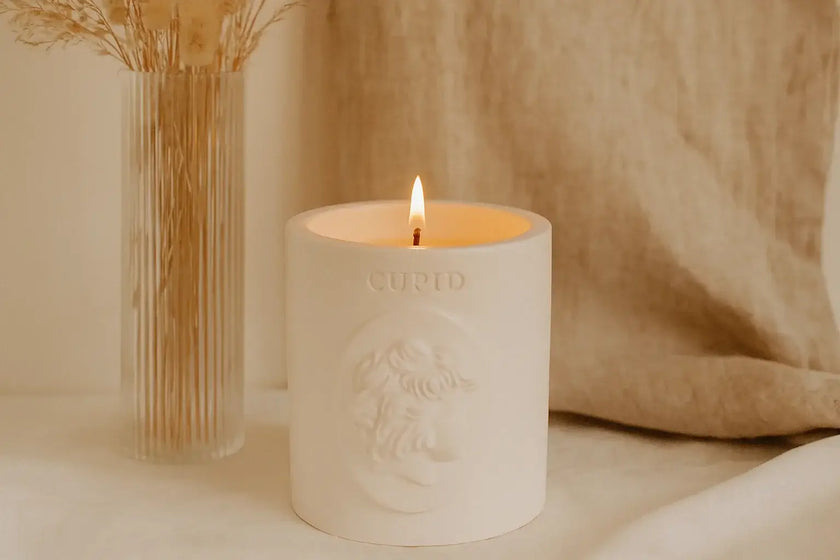 White candle with 'Cupid' Votive's branding on a neutral background