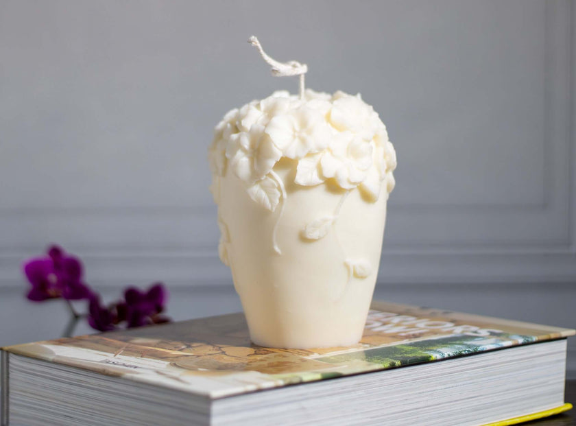 Decorative floral scented soy wax candle styled atop a stack of books, enhancing room decor.