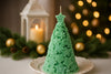 Green Christmas tree-shaped candle on a white plate with festive background