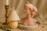 Sculptural candle set with woman bust and mushroom lamp-style candle beside gold candlestick