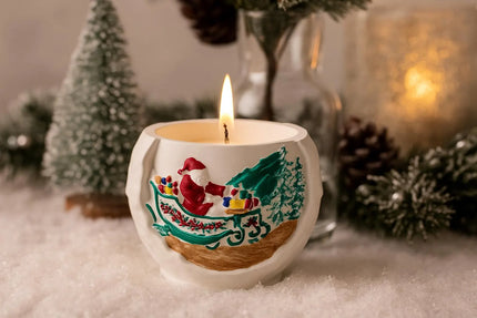 Decorative candle in a mug with a Christmas design, surrounded by festive elements.