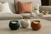 Three ceramic candle holders with candles on a coffee table in a living room setting.