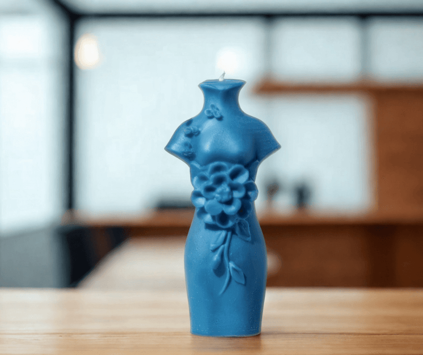 Blue sculptural candle in the shape of a dress with floral details, adding elegance to any decor.