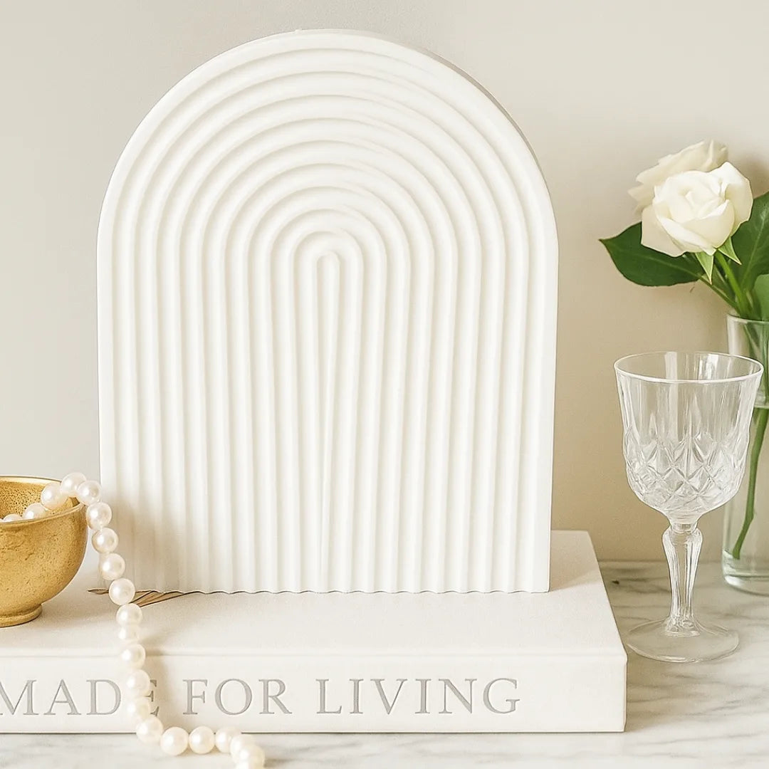 Decorative white arch sculpture on a surface with books and a glass of water.