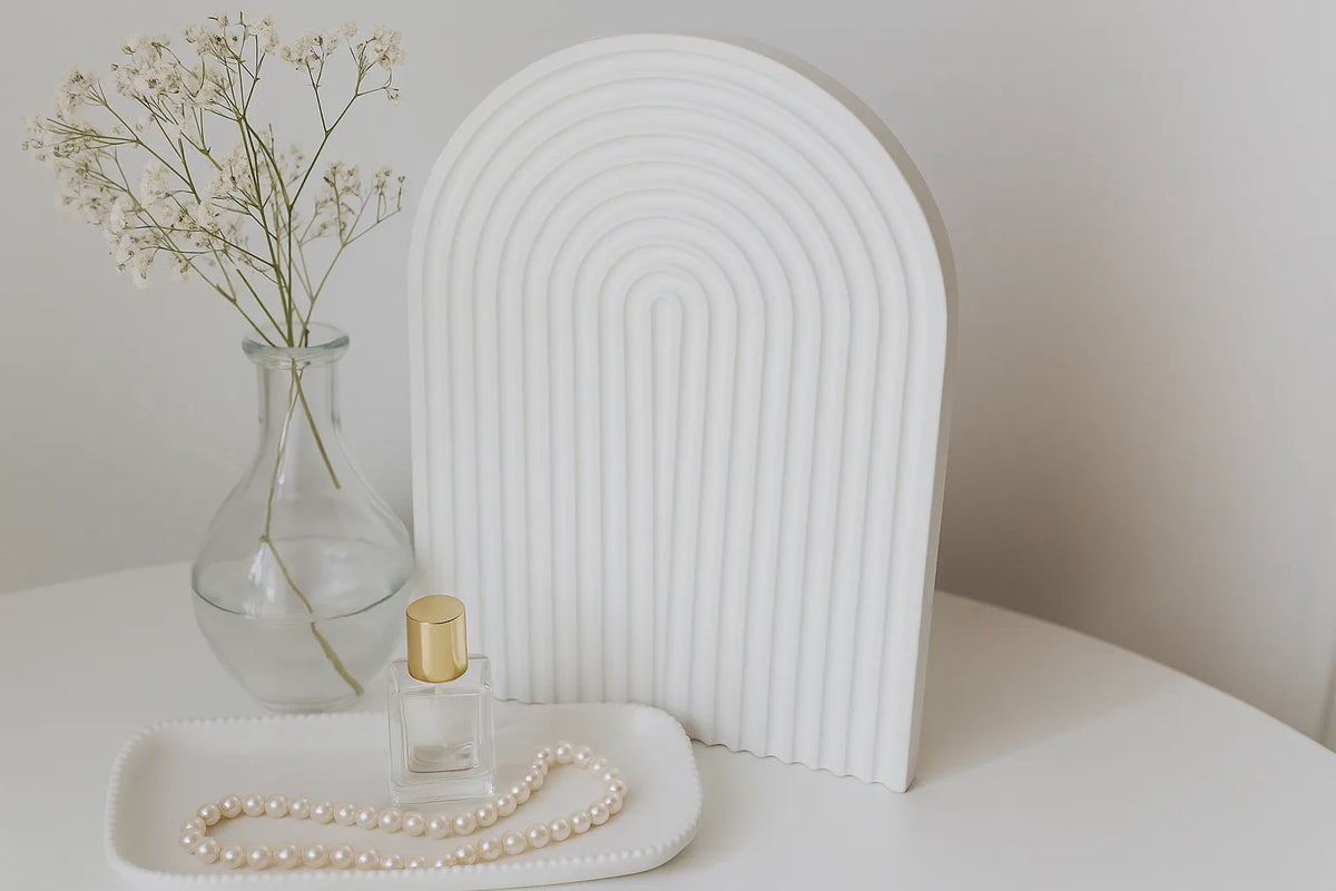 Decorative setup with a vase, perfume bottle, and pearls on a white surface.