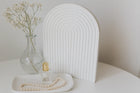 Decorative setup with a vase, perfume bottle, and pearls on a white surface.