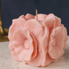Pink floral candle with a visible wick on a neutral background